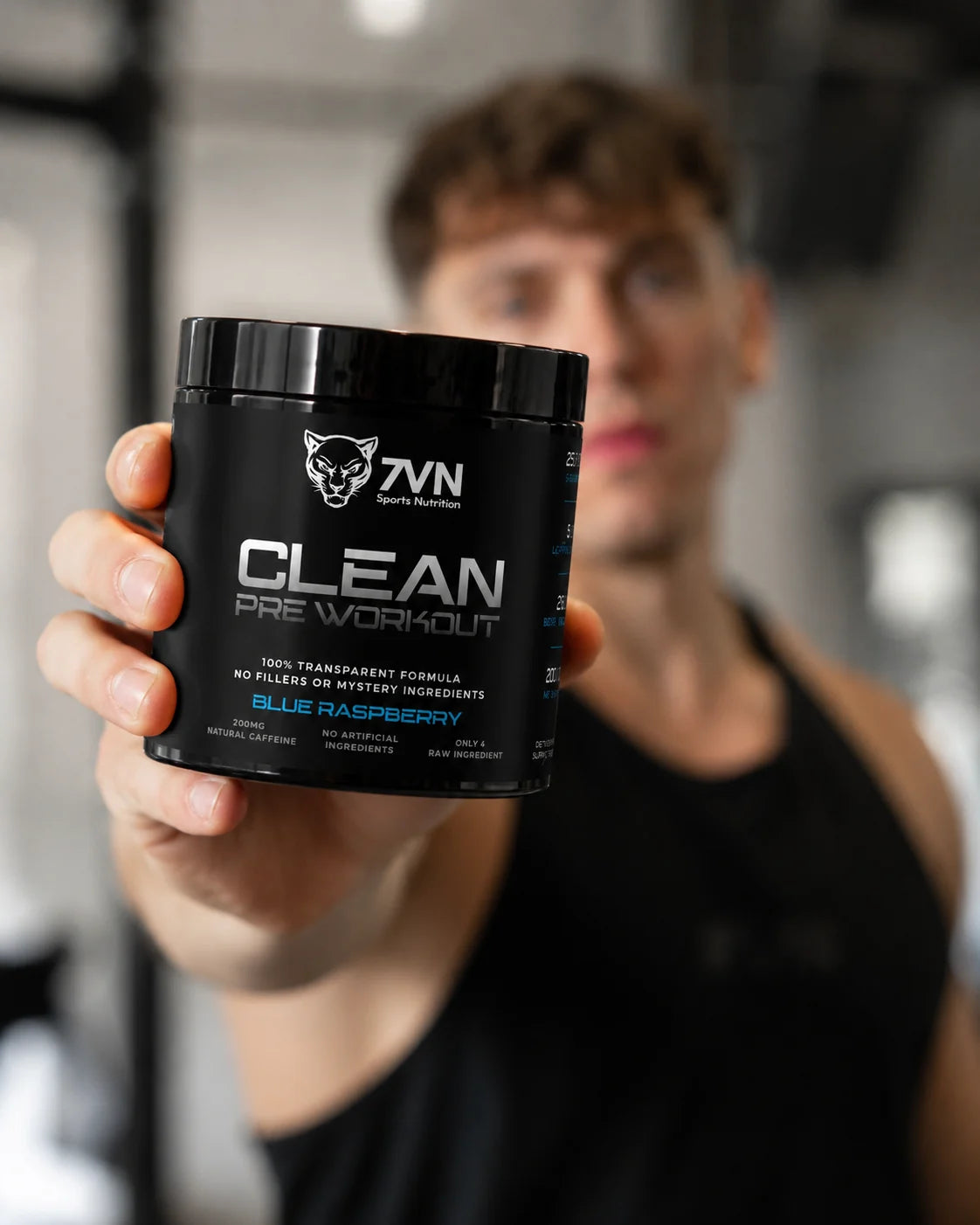 Athlete holding branded 7VN CLEAN Pre Workout in a gym